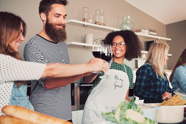 Best friends toasting with wine in kitchen