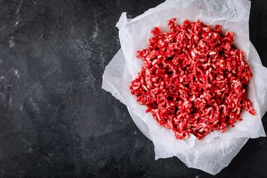Raw ground minced meat and seasonings on dark background