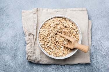 Oats or oat flakes in bowl on linen textile