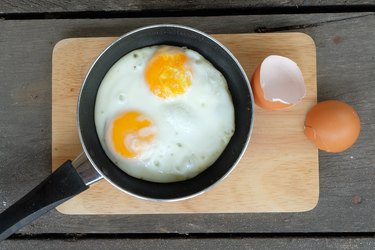 Directly Above Shot Of Fried Egg In Frying Pan On Cutting Board Over Table