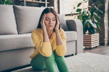 Close up photo of frustrated ill girl sit floor suffer headache migraine pain have health problems close eyes in house living room