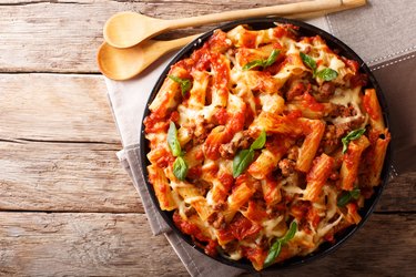 Pasta ziti with bolognese sauce and cheese close-up. horizontal top view, rustic style