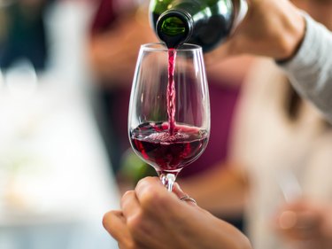 Cropped Hands Pouring Red Wine In Wineglass