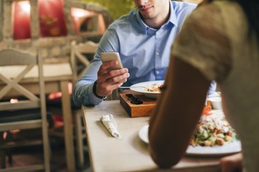 一名男子在餐厅吃饭时看手机