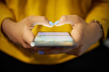 A woman's hands typing on her smartphone screen