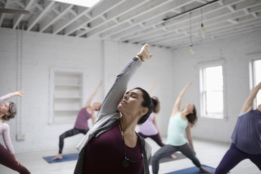 Focused woman practicing yoga reverse warrior pose in yoga class