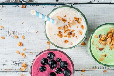 Top view of three colorful milkshakes or smoothies on a wooden table