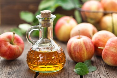 a table of apples and a bottle of apple cider vinegar, as a natural remedy for bug bite relief