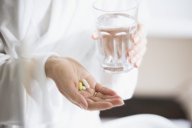 Woman taking vitamins with glass of water