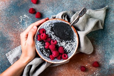 Activated charcoal smoothie and chia seed pudding bowl, vegan detox dessert with raspberry and coconut milk. Overhead, top view, flat lay