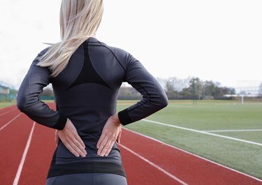 Back Pain. Athletic fitness woman rubbing lower back.