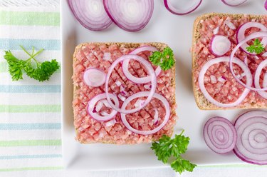 german sandwich mettbrotchen, bun and raw meat with onion and parsley, closeup