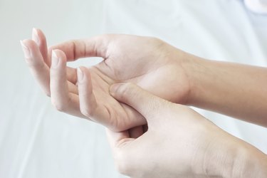 woman pressing the middle of her palm with her thumb to relieve pain due to a tendinitis caused by an excessive use of computer