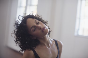 Calm young female dancer stretching neck in dance studio