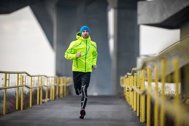 Male athlete running over the bridge