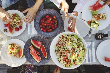 Directly above shot of friends enjoying lunch at picnic table on sunny day