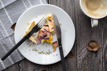 Leftover breakfast on a white plate with a knife and fork