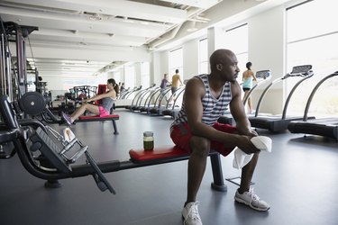 Pensive man resting on bench at gym during mindful workout