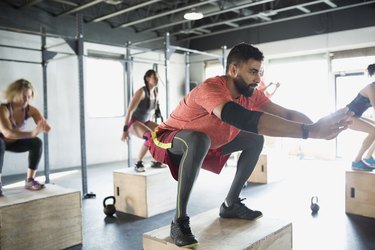 Focused man does jump squats in gym exercise class for benefits of CrossFit