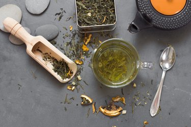 cup of green tea and dried tea on grey stone table