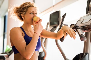 运动的女人吃preworkout吃苹果和一个健身房。