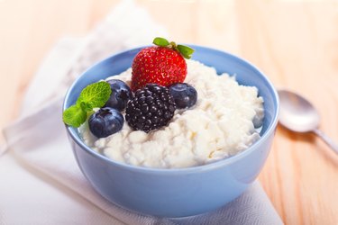 A blue bowl full of cottage cheese with berries on top