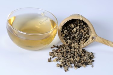 Cup of tea with dried black cohosh root and tea strainer, close up