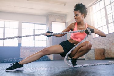 Young woman pulling rope at gym.