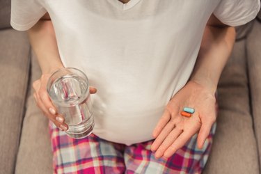 Pregnant woman at home taking vitamins