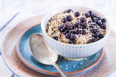 Vegan superfood breakfast with porridge, almond milk, blueberries and roasted quinoa