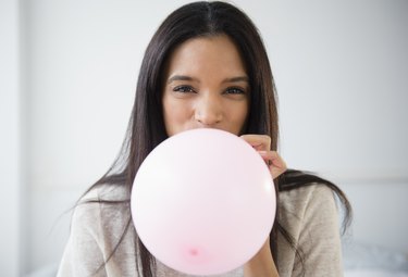 Mixed race woman blowing up balloon