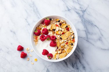 Healthy breakfast. Fresh granola, muesli with yogurt and berries on marble background. Top view.