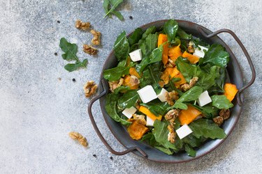 Concept diet menu, Vegan food. Salad with baked pumpkin, feta, cheese and vinaigrette dressing on stone background. Top view flat lay. Free space for your text.