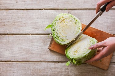 Woman cuts cabbage on two parts