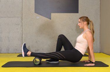 Young woman exercising with roller at gym