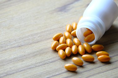 supplement pills and container on wooden table