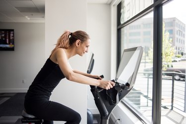 Woman working out on exercise bike in workout room