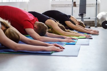 Group exercise yoga class performing child pose