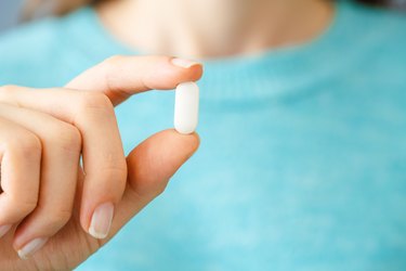 Hand holding white pill