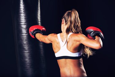 Attractive woman boxer wearing a black sports bra and red gloves