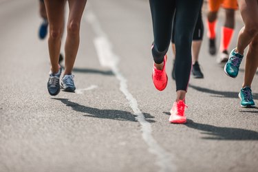 Group of unrecognizable athletes running a marathon on the road.