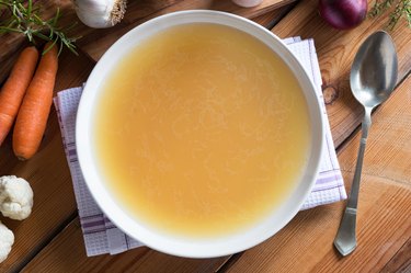 Bone broth made from chicken on a wooden table