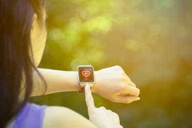 Female runner checking heart rate on smart watch outdoors