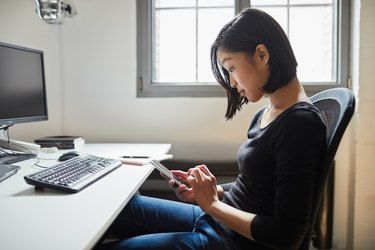 Young woman using smart phone at work.