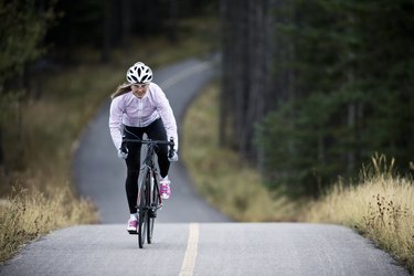 A woman rides her road bike along the Trans Canada Trail bikepath near Canmore, Alberta, Canada in the autumn.