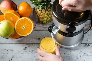 Preparing fresh orange juice. Fruits in background