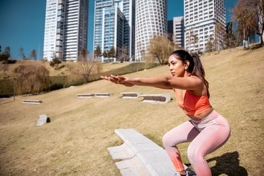 Young woman doing a leg toning workout in the morning in a public park