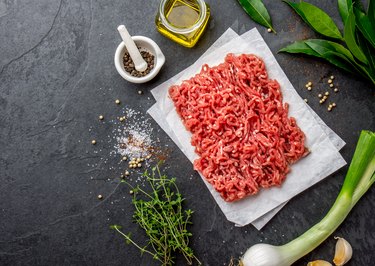 Mince. Ground meat with ingredients for cooking on black background. Minced beef meat. Top view