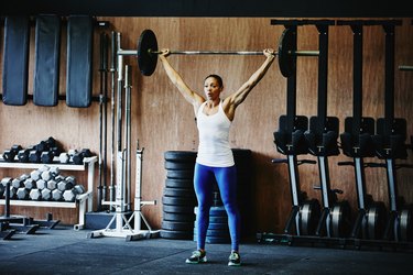Woman pressing barbell overhead during workout