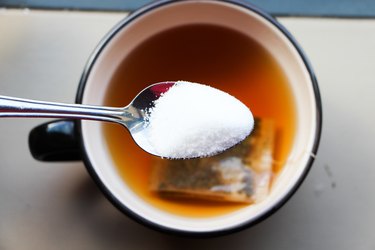 Close-Up Of Sugar In Spoon Over Drink On Table